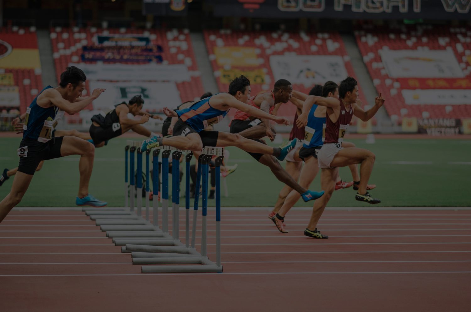Athletes clearing hurdles in a track race